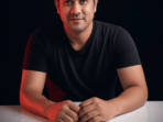 A 40 years old man sitting down, black background with shadow (1)